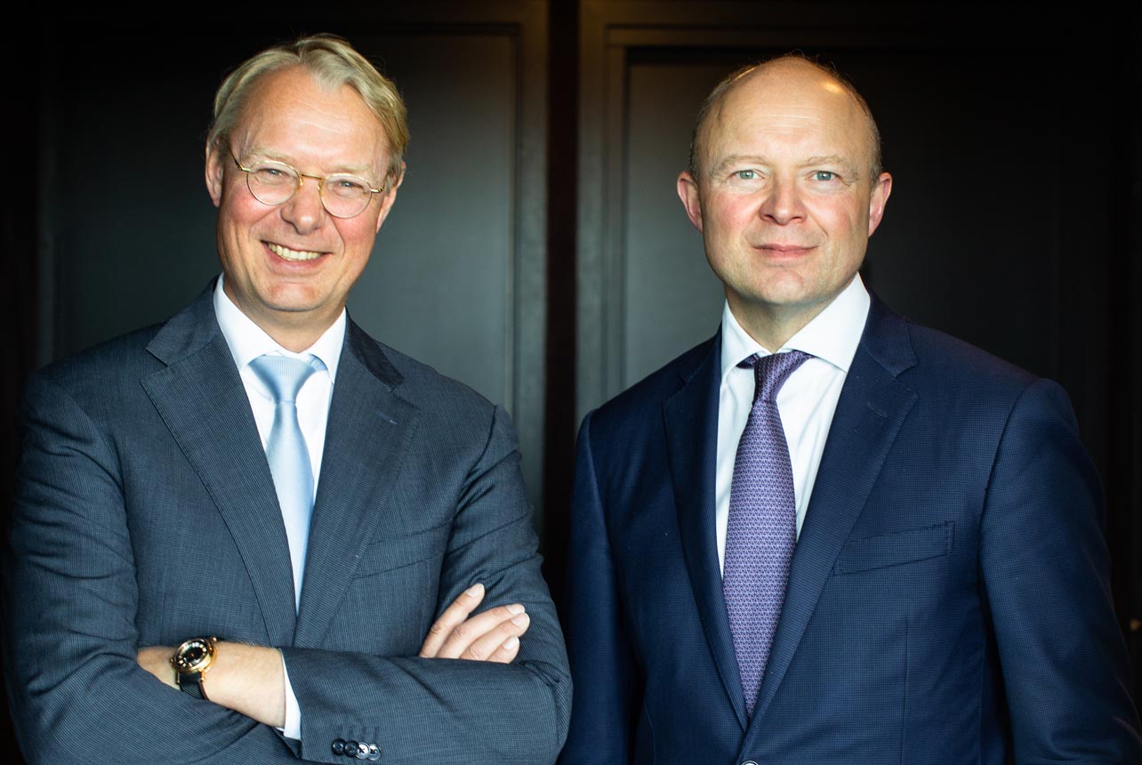 two men in suits posing for a picture