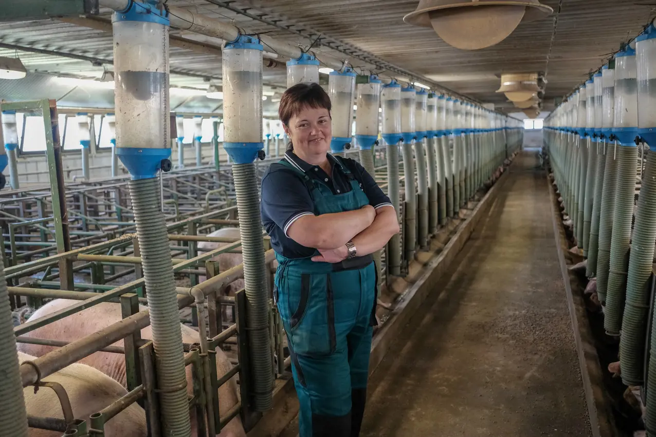 A woman standing in a barn with her arms crossed.